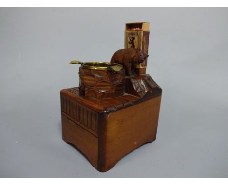 A BLACK FOREST MUSICAL CIGARETTE BOX, having carved standing bear atop stump before match box with brass ashtray with cigaret