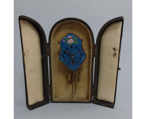 A CASED MINIATURE ENAMEL CLOCK, the blue enamelled shield shape clock modelled as hanging wall clock having floral decoration