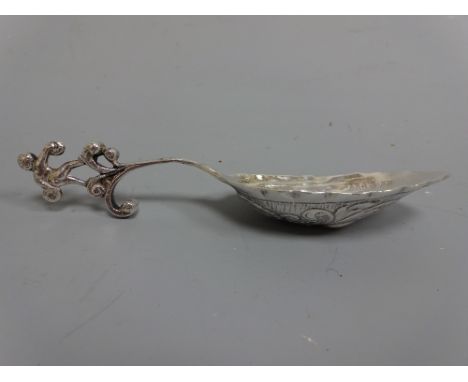 A SILVER TASTING SPOON, having embossed scroll and fleur de lys decoration to bowl, figural capital, import London 1904 mark,