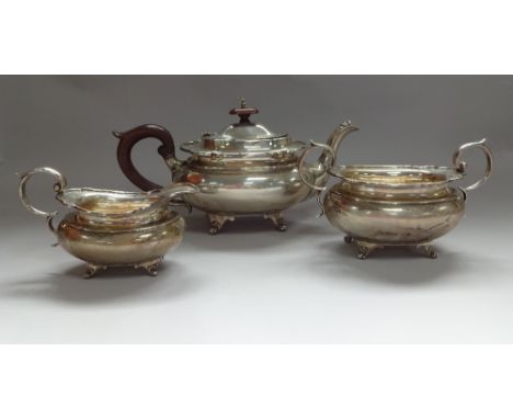 A SILVER THREE PIECE TEA SERVICE, of boat form with wavy rims set on scrolled feet, all having high loop handles, the teapot 