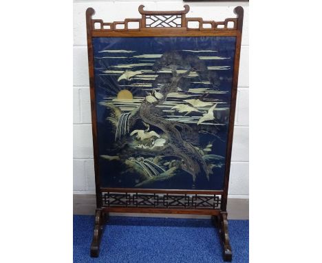 AN ORIENTAL ROSEWOOD FRAMED FIRE SCREEN, having pagoda top over cranes in trees before sunshine sky embroidery with pierced b