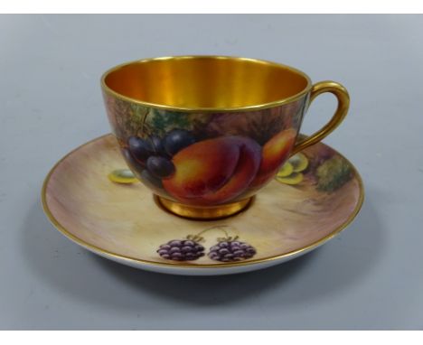 A ROYAL WORCESTER CABINET CUP AND SAUCER, hand painted with peaches, grapes and berries to mossy bank, gilt interiors, signed