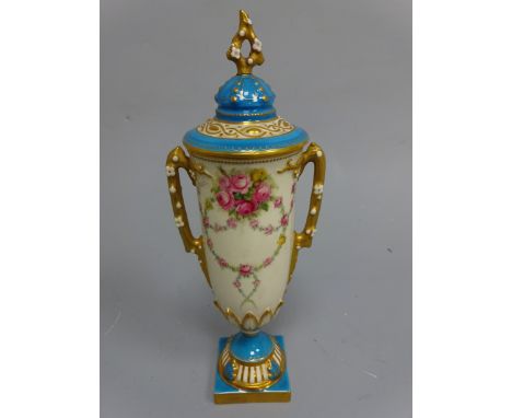 A ROYAL WORCESTER PEDESTAL VASE AND COVER, the urn body hand painted with floral swags, signed E Phillips, naturalistic bloss