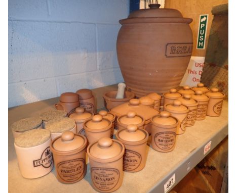 Shelf of terracotta spice jars bread bin vinegar oil containers etc 