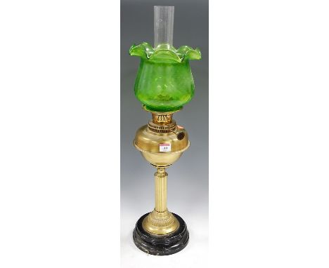 An early 20th century brass oil lamp, having green tinted frilled glass shade and brass reservoir, on a fluted column and cir