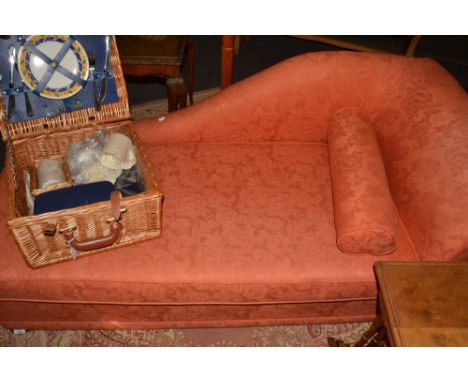 A contemporary chaise longue style sofa bed, upholstered in terracotta coloured fabric