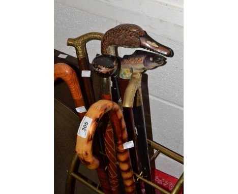 A novelty walking stick, the handle carved as a duck's head with souvenir badges, another with brown trout, a smaller duck, o