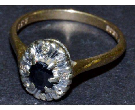 A diamond and sapphire cluster ring, central oval dark blue sapphire, flanked by four illusion set diamonds, 9ct gold shank, 