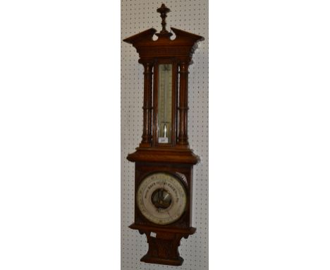 An Edwardian oak wall hanging barometer/thermometer,J P Cutts Sutton & Son, Gothic frame, twin column sides, silvered dial .c