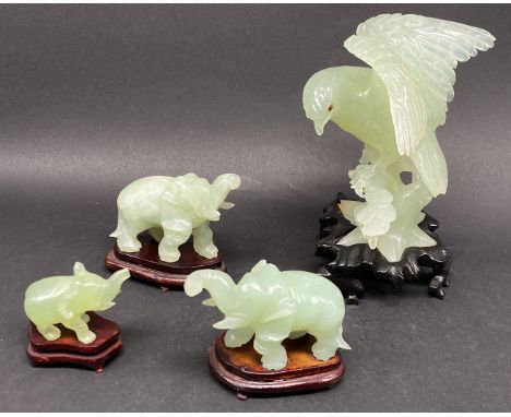 Vier Figuren aus hellgrüner Jade: Adler auf einem Ast sitzend, H. 13,5 cm; sowie drei Elefanten, zwei größere Elefanten 7 x 9