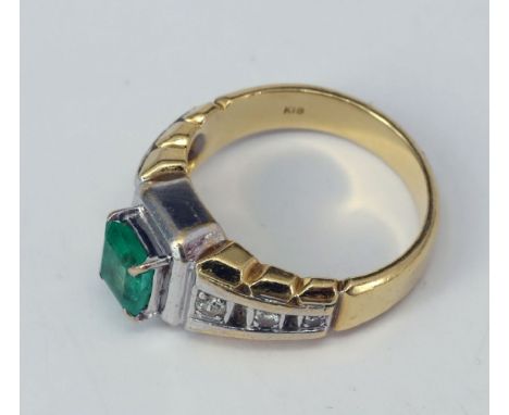 Damenring, 750er GG, 9 g. Mit zentralem Smaragd in Baguetteschliff (minimal bestoßen), dazu insg. 6 Diamanten in Schiene, Geb
