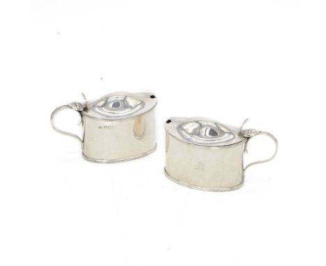 Pair of Edwardian silver mustard pots, of oval form with reed borders and palmette thumb pieces to hinged covers, opening to 