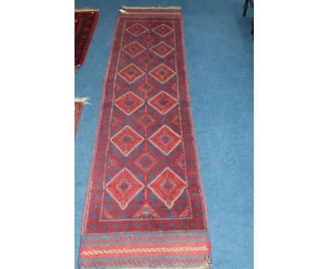 A modern Baluchi runner, midnight blue and madder red, with hooked medallions and kilim ends, 60cm x 164cm