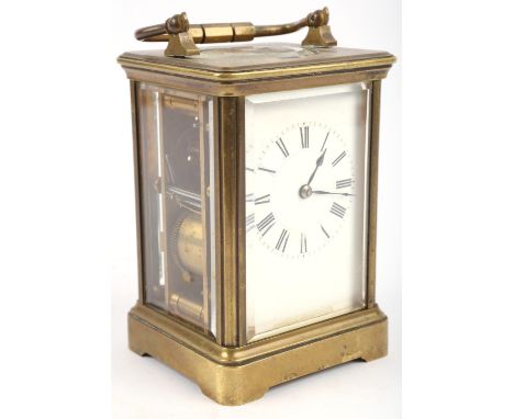An Edwardian brass carriage clock, the white enamel face with Roman numerals, the glazed sections bevelled and the top with a