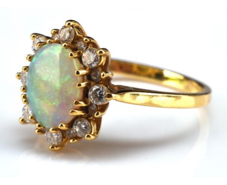 Opal and diamond cluster ring, with an oval cabochon cut opal weighing an estimated 0.75 carat, surrounded by round brilliant