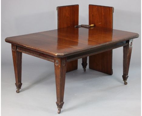 A late Victorian mahogany extending dining table with moulded edge &amp; canted corners to the rectangular top, having two ad