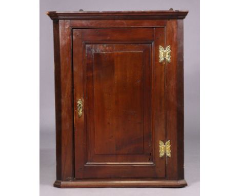 A Georgian fruitwood hanging corner cupboard fitted with three shaped shelves enclosed by a fielded panel door, 64.5cm wide x