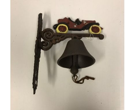 A modern painted cast metal wall bell with vintage car decoration