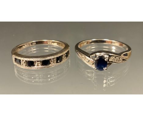A diamond and sapphire ring, central oval deep blue sapphire above three stone diamond inset shoulders, white metal shank, st