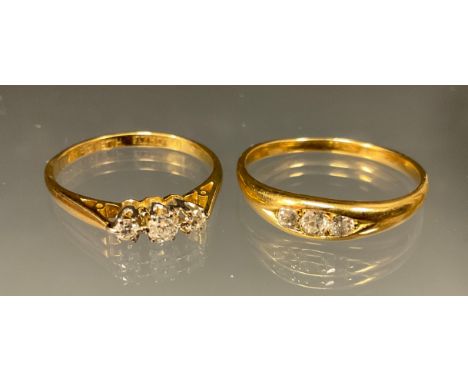 A diamond three stone and gold coloured metal ring; another three stone ring (2) 