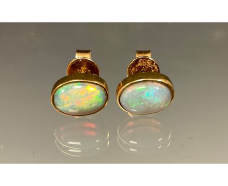 A pair of opal cabochon earrings, flashing green, blue, orange and red colour play, yellow metal mounts, stamped 585,14k to b