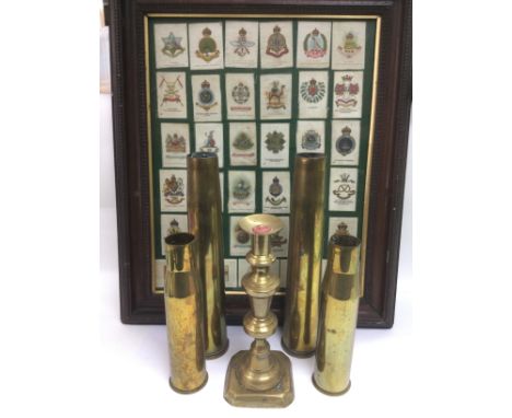 A framed set of silk cigarette cards of regimental insignia plus four WW2 artillery shells and a brass candlestick (6). Shipp