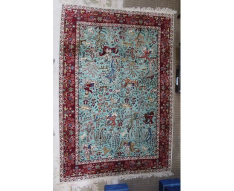 A 20TH CENTURY PERSIAN RUG having central blue field with all over hunting scene, archers on horseback amidst stylised trees,