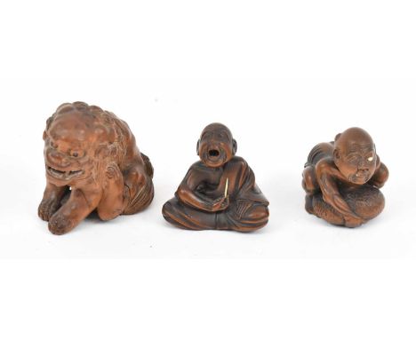 Three Japanese carved wooden netsuke comprising temple lion and two figures.