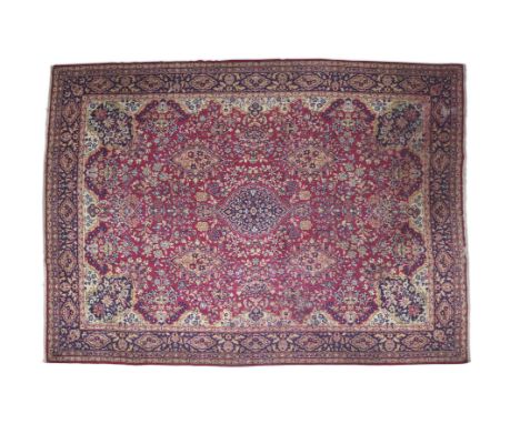 A PERSIAN RED GROUND WOOL CARPET, mid-20th Century, the central reserve woven with a blue medallion, framed within four orang