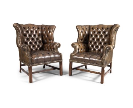 A PAIR OF MAHOGANY FRAMED WING BACK ARMCHAIRS, upholstered in a green close nail and button back hide, raised on square chann