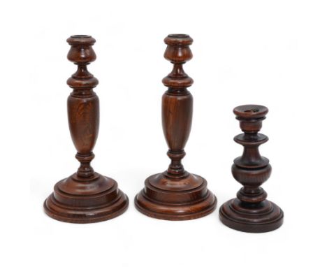 Pair of turned pine candlesticks with baluster stems, H30cm, together with a similar smaller candlestick (3)
