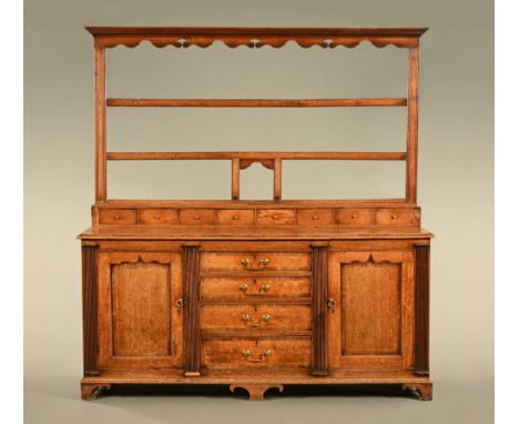 A late 18th century oak Welsh dresser, the upper section with plate rack over a lower section with two cupboard doors flankin