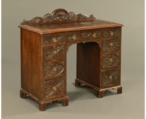 A late 19th century kneehole desk, with upstand and carved drawer fronts with brass drop handles and raised on bracket feet. 