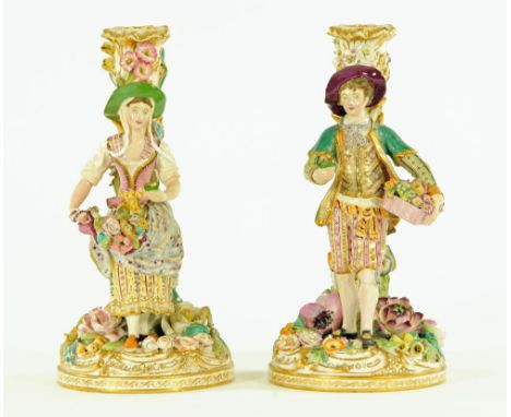 A pair of 19th century porcelain figural candlesticks, unmarked.  Height 23 cm. CONDITION REPORT: Both candlesticks have had 