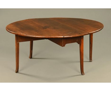 A large antique oak gate legged dining table, twin drop flap raised on shaped legs with outswept legs with outswept feet.  He
