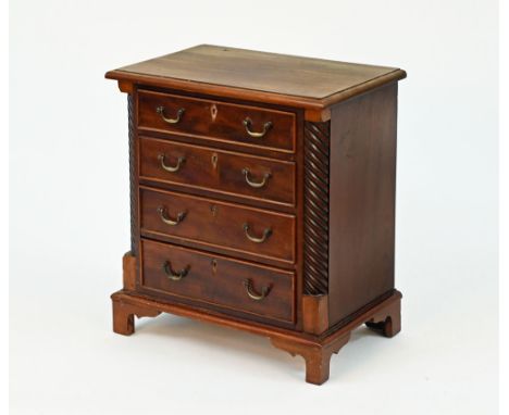 A Victorian style miniature chest of drawers, with moulded edge above four graduated drawers and raised on bracket feet.  Hei