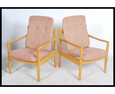 A pair of 20th century Ercol staff chairs. Light beech wood turned construction with shaped elbow rests having upholstered se