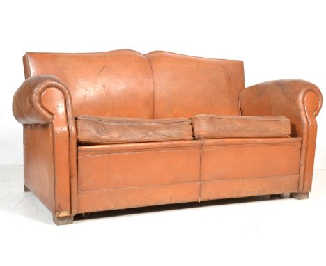 A 1930's French Art Deco Moustache back club settee / sofa in brown distressed leather being raised on straight legs. The sof