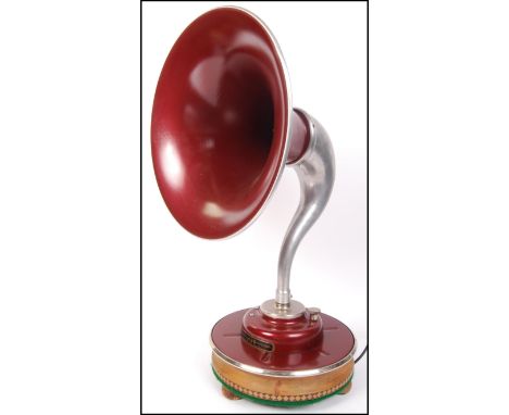 An upcyled gramophone horn and bracket of pressed metal construction with red painted finish being converted to a table lamp.