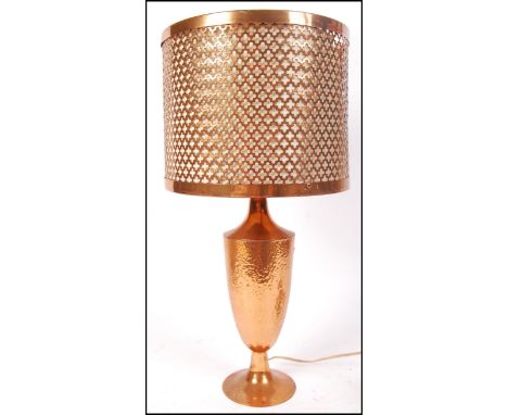 A 20th century contemporary industrial modernist table lamp having a beaten textured urn with lamp atop and a copper fret pie