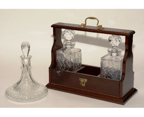 An oak Tantalus with two matching crystal mallet decanters, together with a separate third Edinburgh Crystal ships decanter, 