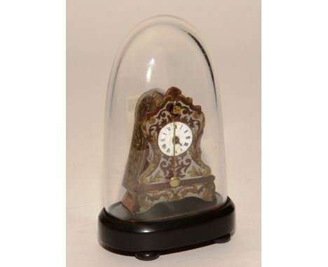 A miniature wood cased mantel clock, with foliate panels on metal mount under glass dome, on ebonised wood stand, 7cm high