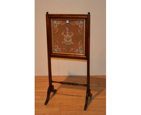 A Victorian mahogany firescreen, with central embroidered panel bearing the Dunlop family crest, under glass, above turned st