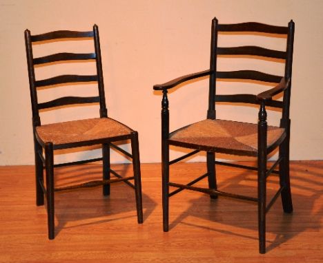 A set of eight country style oak ladder back rush seated dining chairs, comprising of two carver chairs and six side chairs, 