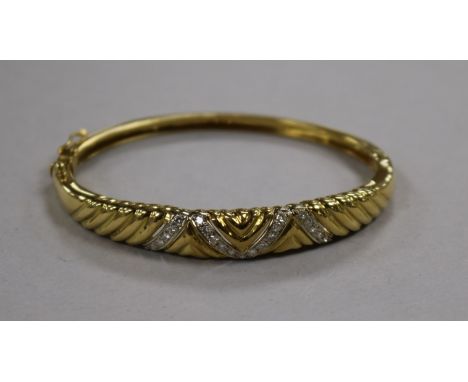 A modern 18ct gold and diamond set hinged bangle.
