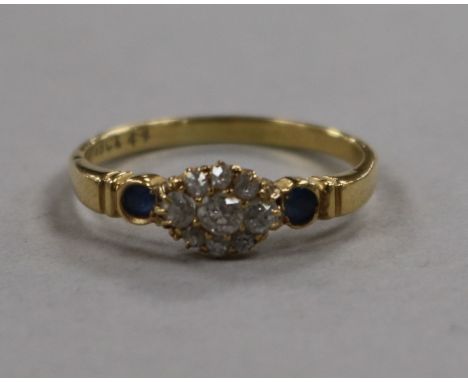 An early 20th century diamond cluster ring with sapphire set shoulders, size R.