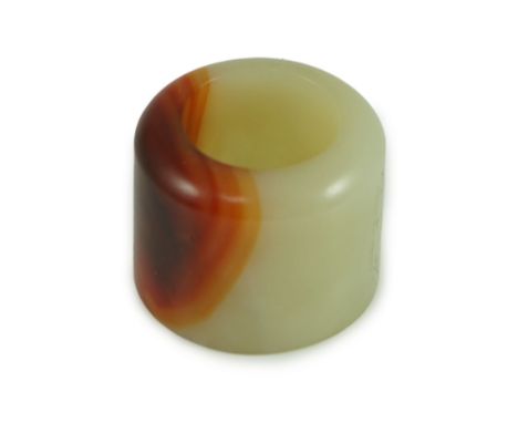 A Chinese pale celadon and russet jade archer's ring, early 20th century 3.4 cm diameterNatural inclusions and veining to the