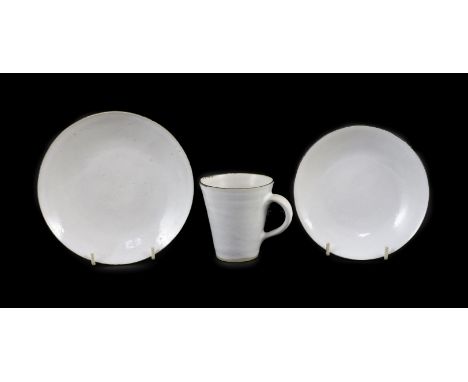 Dame Lucie Rie (1902-1995) a cup, saucer and side plate, c.1959, each white glazed stoneware with manganese rims, impressed L