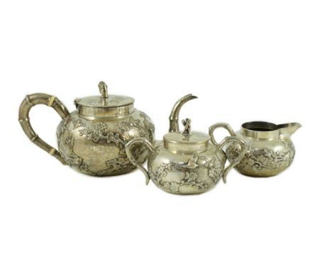 A 19th century Chinese Export silver three piece tea set by Cumshing? decorated with birds amid prunus and faux bamboo handle