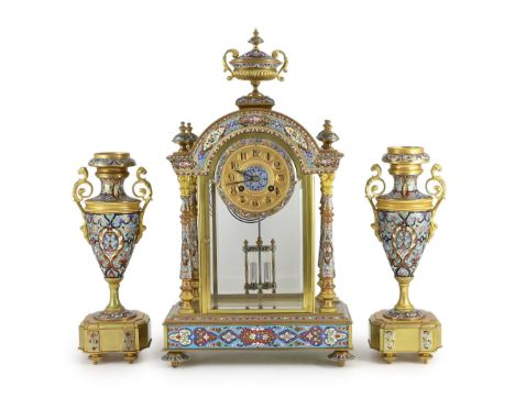 An early 20th century French ormolu and champleve enamel clock garniture, the mantel clock of architectural four glass form w